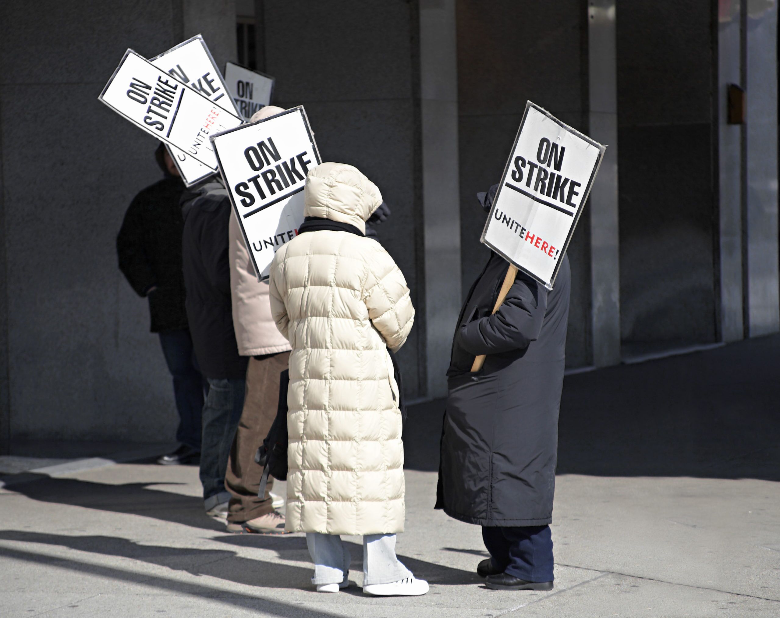 Workers on a picket line carrying signs saying On Strike, Unite Here!