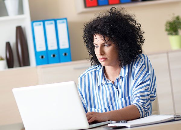 Mujer de mirada seria que usa una computadora portátil