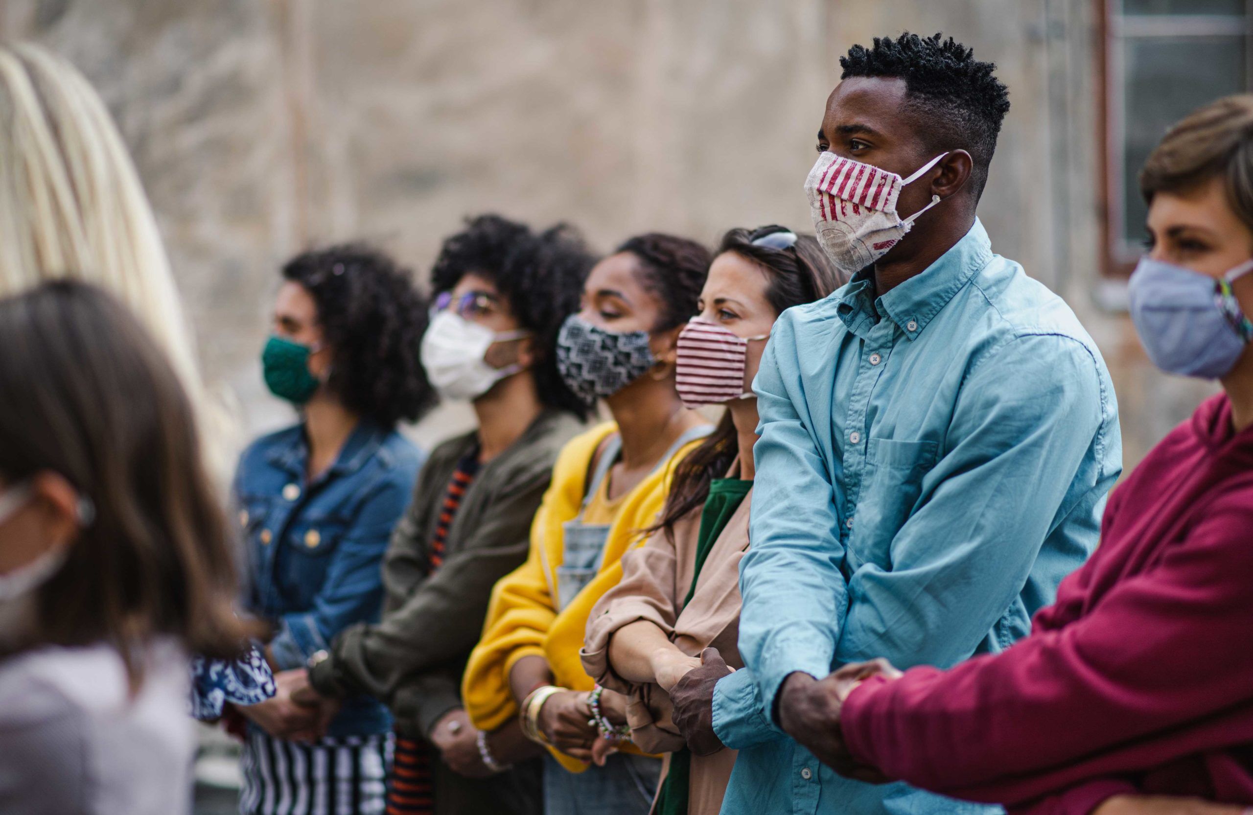 Grupo de manifestantes pacíficos contra la brutalidad policial con máscaras y tomados de la mano tras la muerte de Daunte Wright