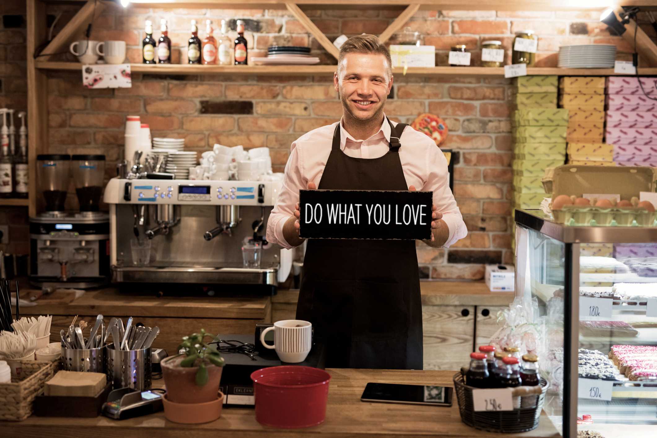 Dueño de una pequeña cafetería con un cartel que dice: Haz lo que amas