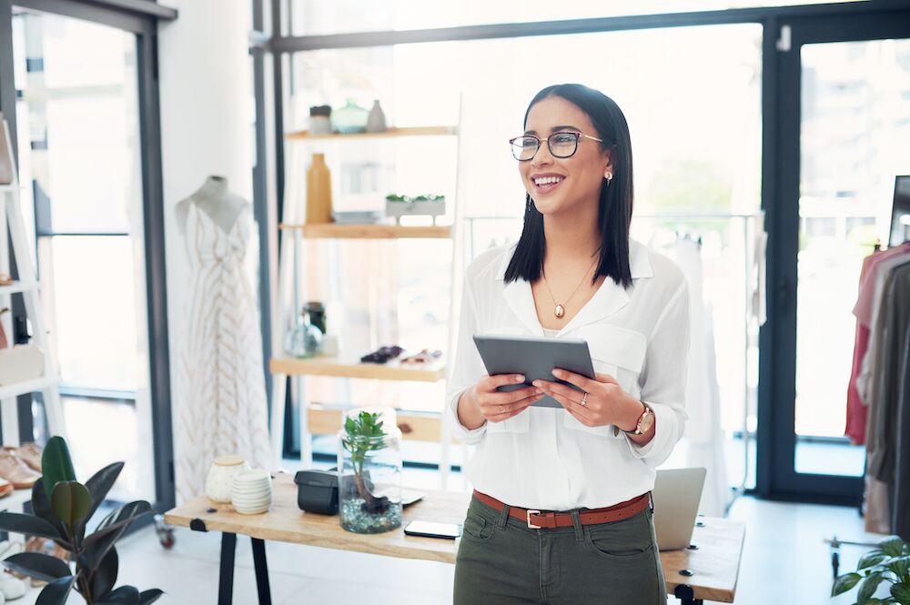 Retail shop business owner holding a tablet and smiling