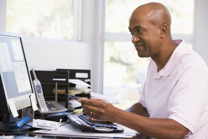 Man looking at computer monitor and paying bills