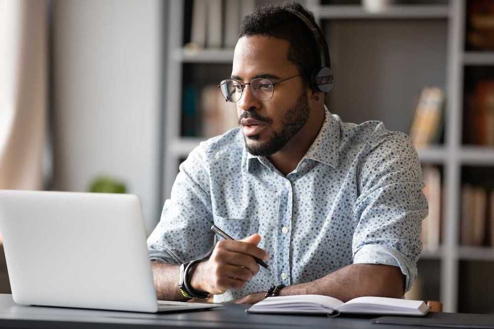 Hombre trabajando desde un escritorio en una computadora portátil con auriculares