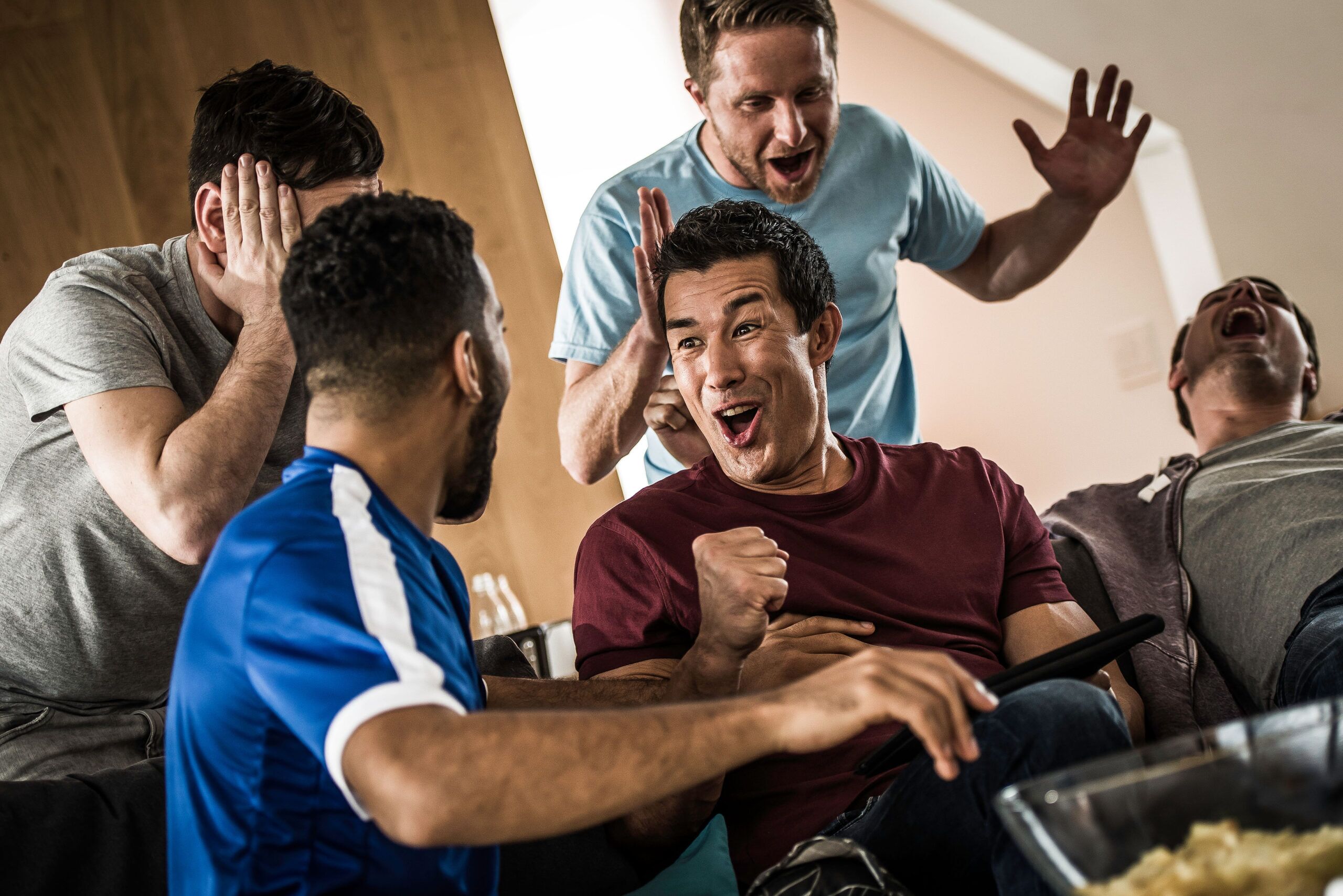 5 male friends celebrating good news viewed on a tablet computer