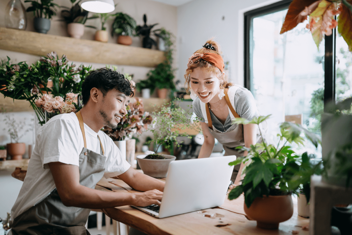 Dos dueños de pequeñas empresas mirando una computadora portátil en una floristería