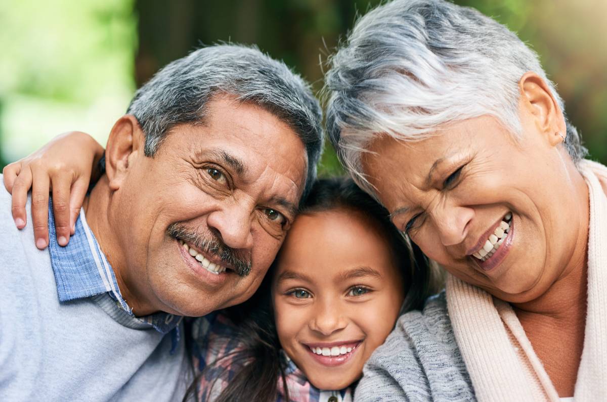 Grandparents hugging their granddaughter.