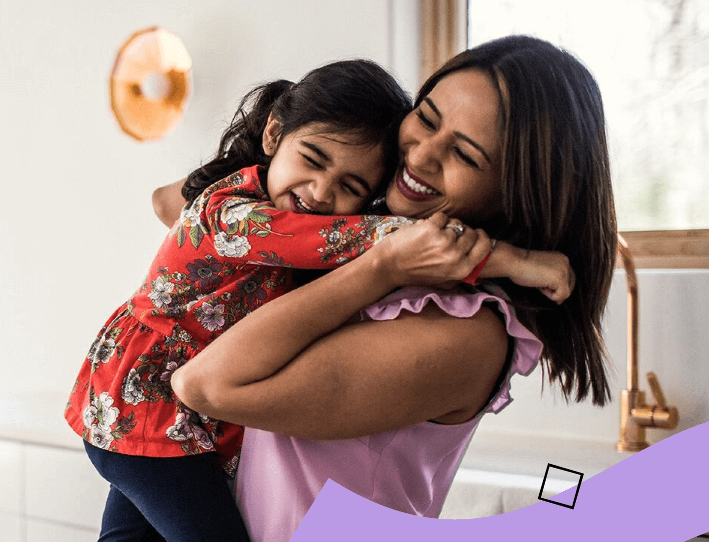 Madre sonriente sosteniendo y abrazando a su hija pequeña.