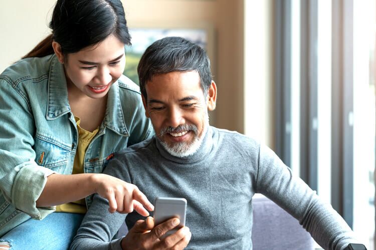 A daughter looking at the LegalShield Personal Plan Coverage & Pricing information with her Father on his phone.