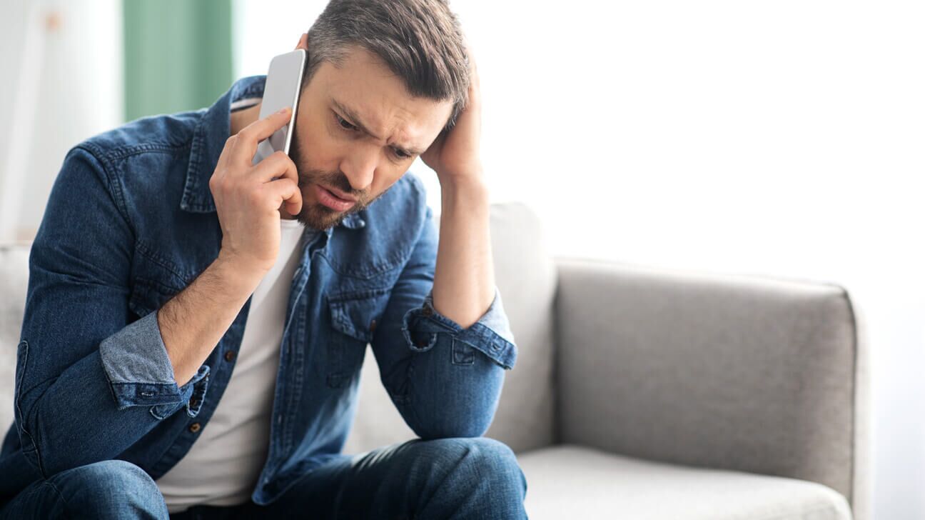 Hombre angustiado hablando por teléfono tratando de recuperar el dinero que se le debe.