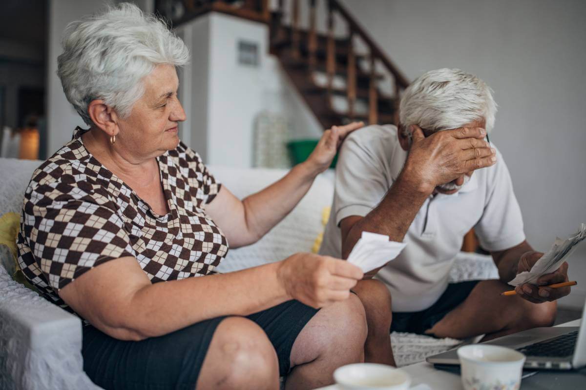 Elderly wife comforting husband after experiencing an elder financial exploitation event.