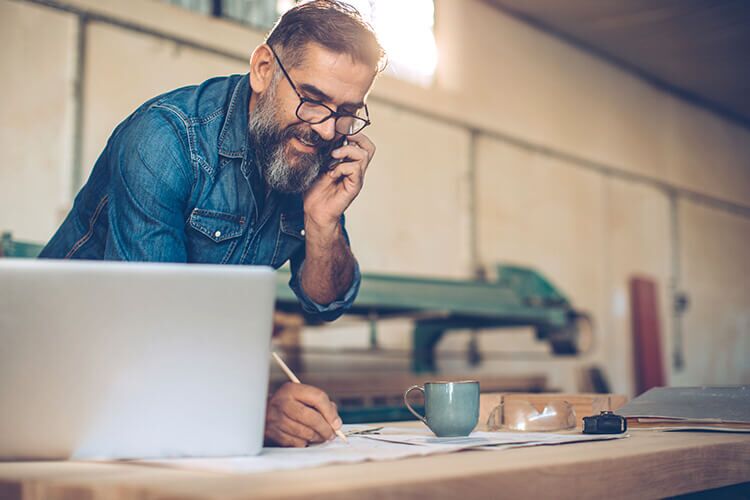 Small business owner talking on the phone and taking notes.