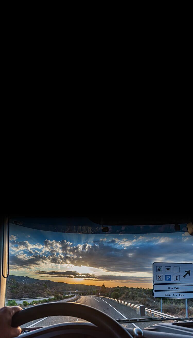 View of the road and landscape through the windshield of a truck