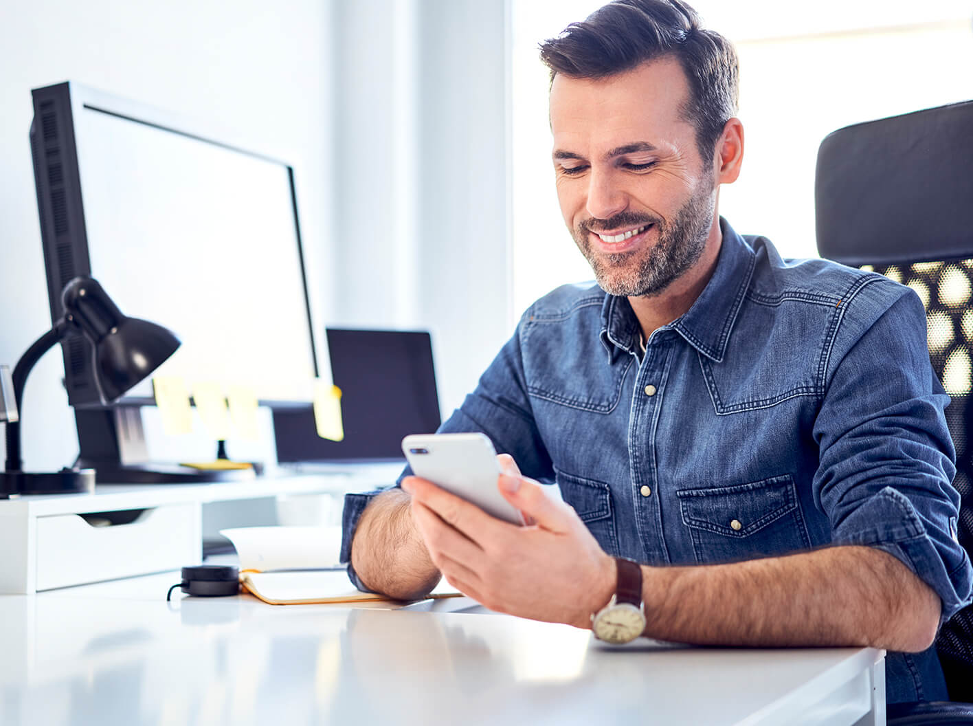 Smiling man typing on smartphone.