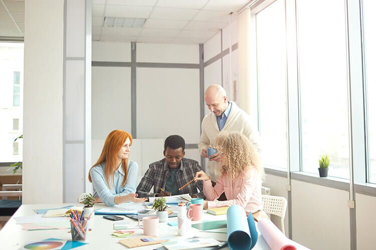 A group of people sit around a table looking at various papers.