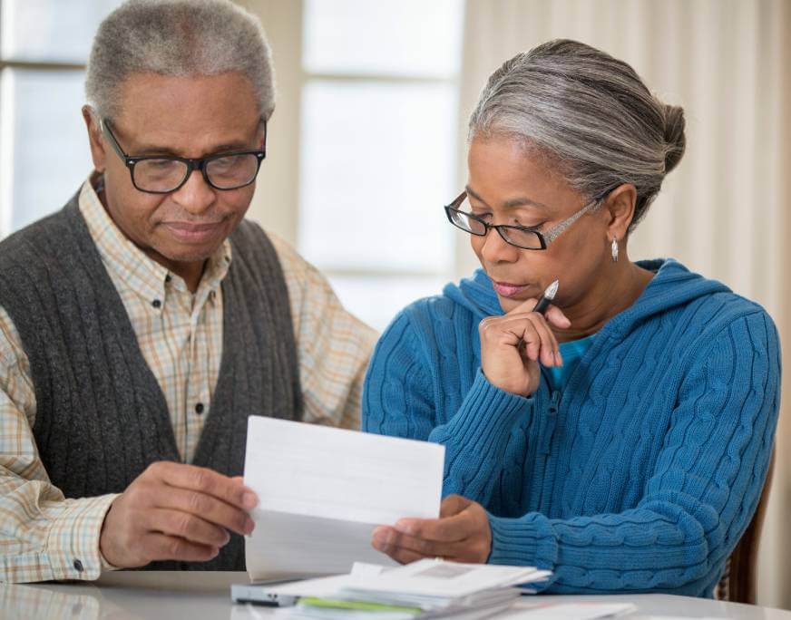 An older man and woman reviewing a car repossession notice in their home.