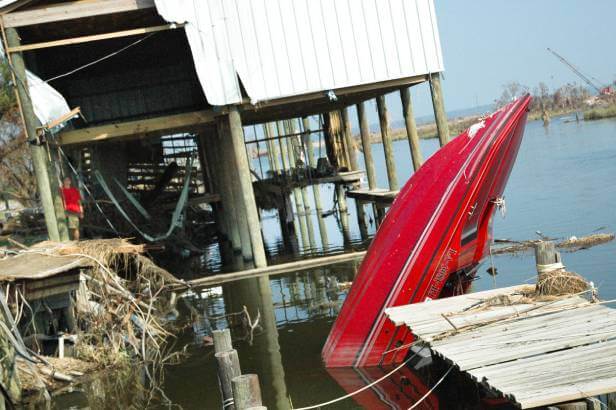 Hurricane damage house and boat upside down in flood water.