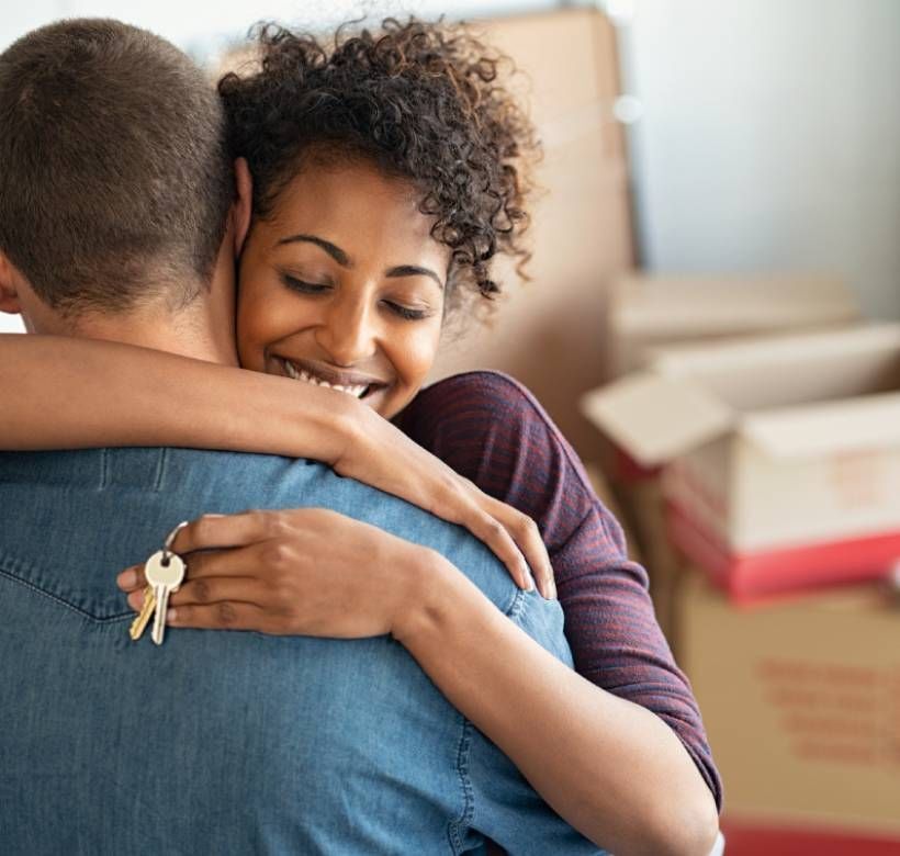 Una joven pareja se abraza en su nuevo hogar.