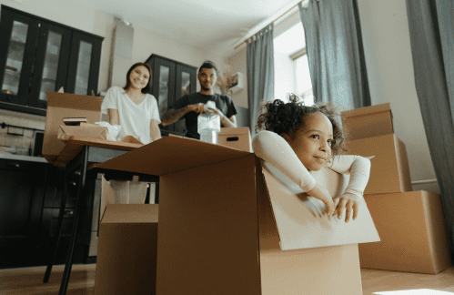 Una madre, un padre y una niña pequeña desembalan cajas en su casa alquilada.