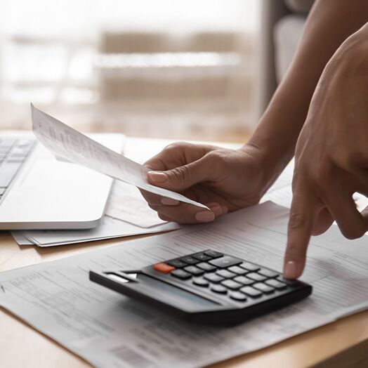 Un pequeño empresario utilizando una calculadora para totalizar gastos.