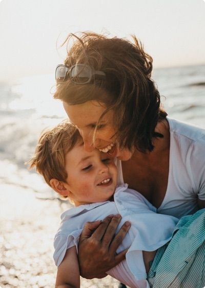 Una madre sonriente en la playa con su hijo.