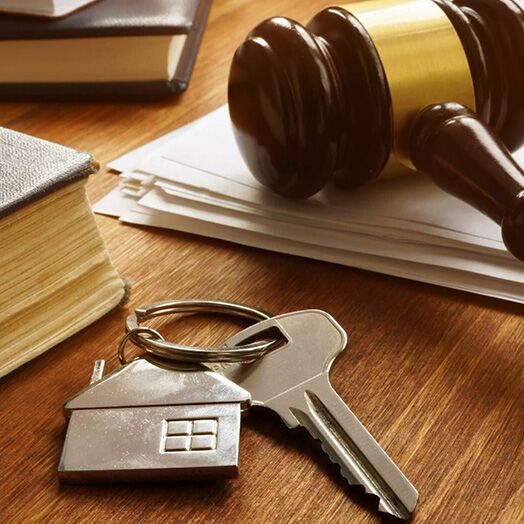 Mazo del juez sobre un escritorio junto a las llaves de casa, libros jurídicos y una pila de papeles.