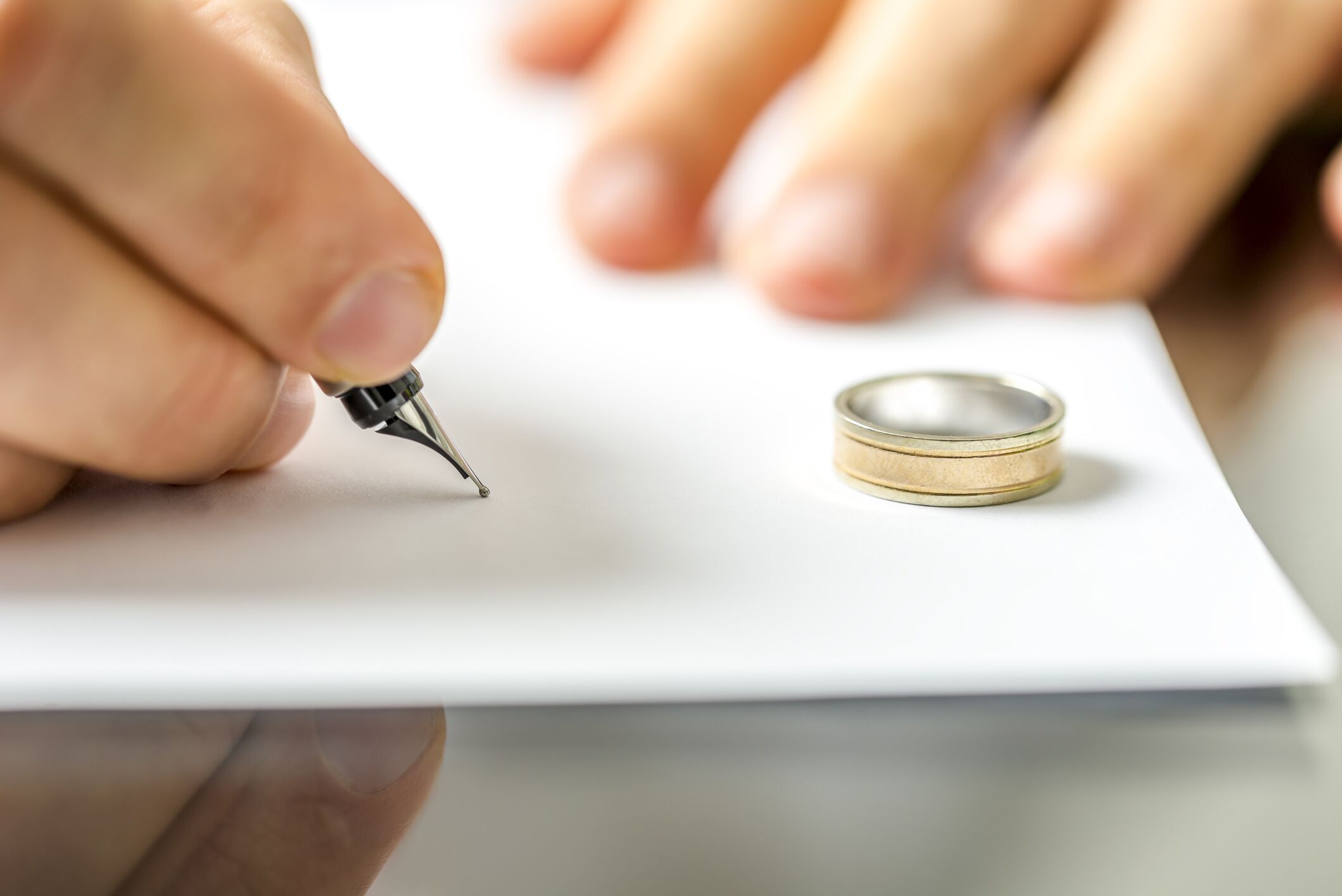 Hombre firmando un documento de divorcio con su anillo de boda cerca.