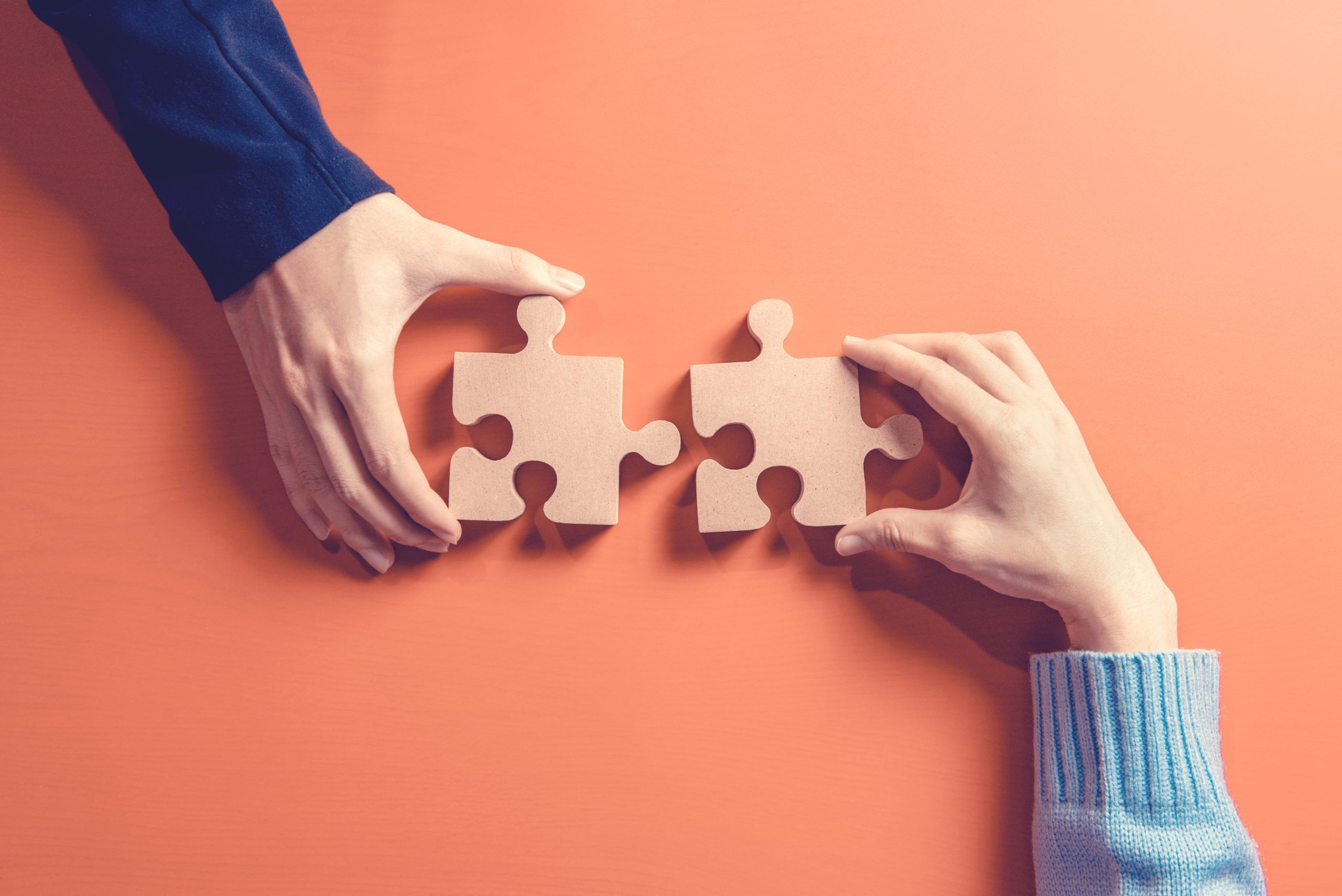 Two hands holding jigsaw puzzle pieces. Concept for teamwork.