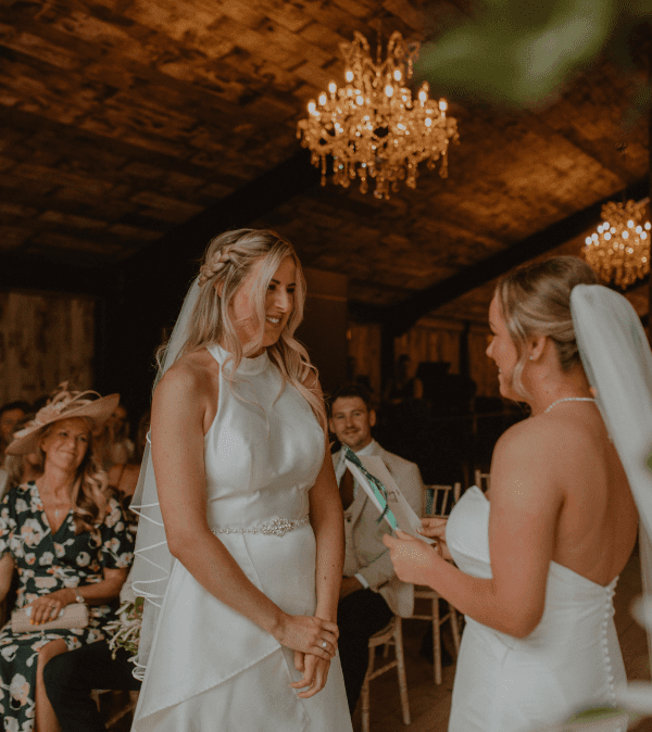 2 brides during their gay wedding reciting vows to each other.