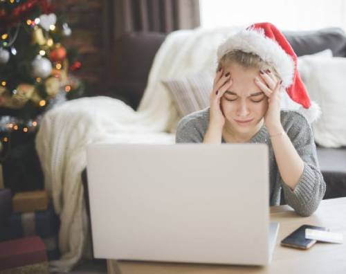 Upset woman wearing a Santa hat looking at her laptop computer.